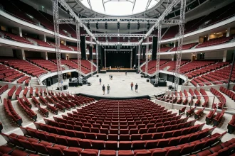 Vue panoramique de l'intérieur de la salle Bercy depuis les gradins supérieurs avec rangées de sièges rouges et scène centrale